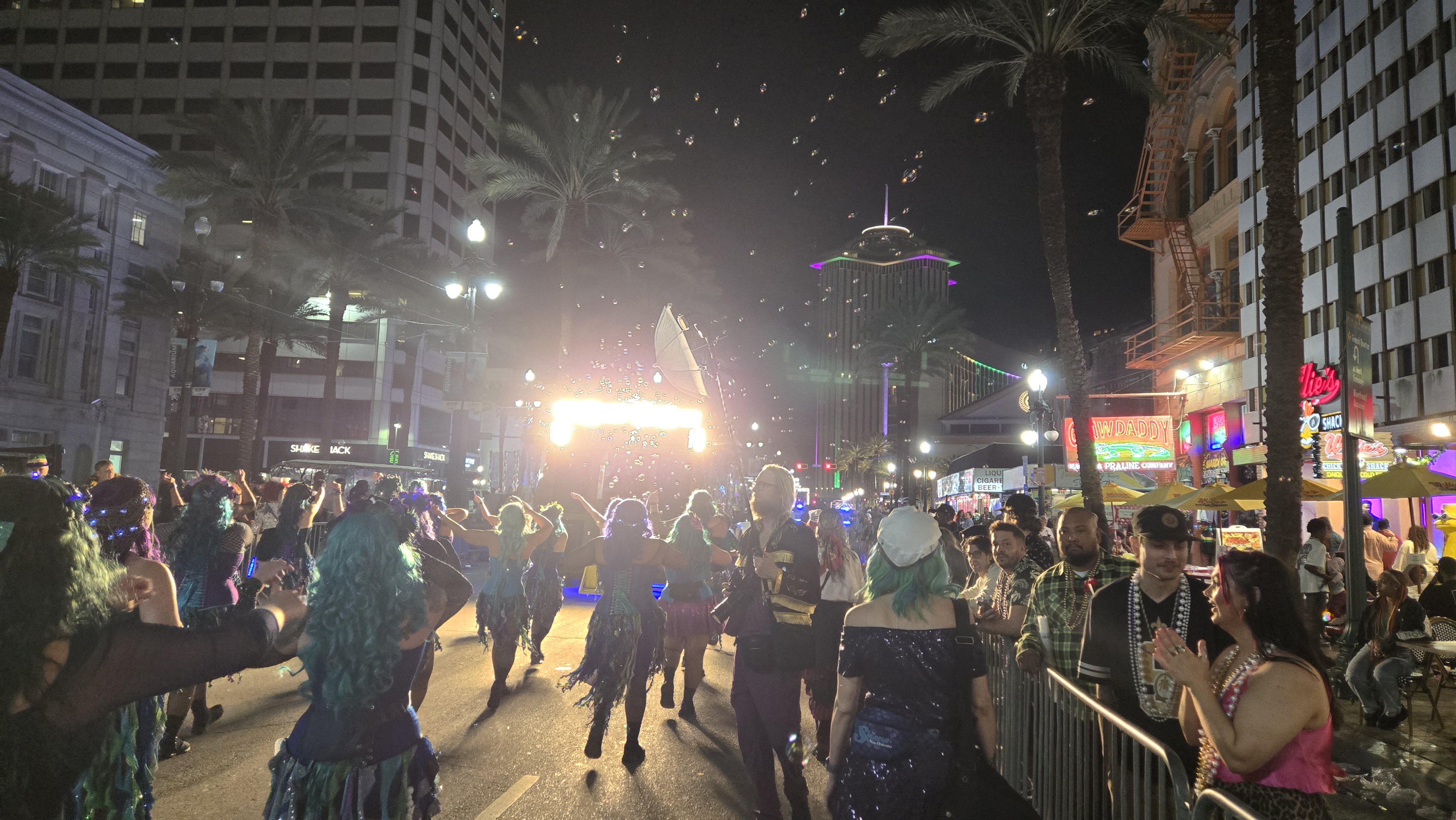 A nighttime parade with crowds and illuminated buildings in New Orleans